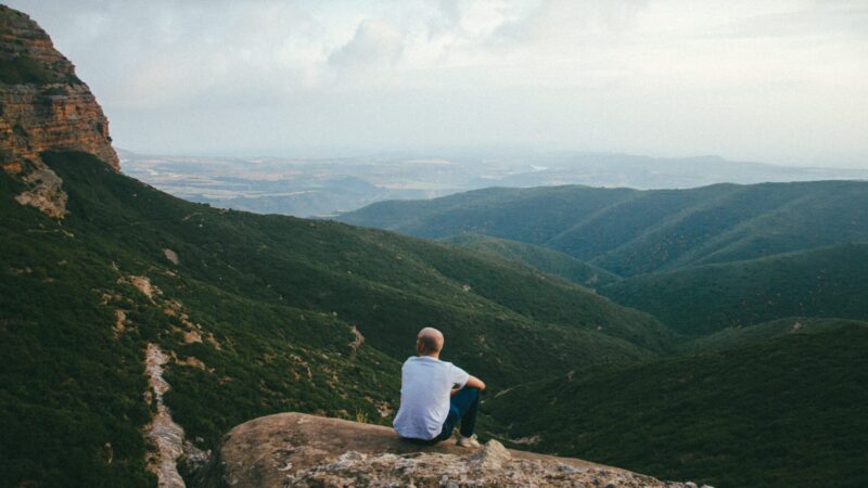 崖の上で寂し気に座る男性