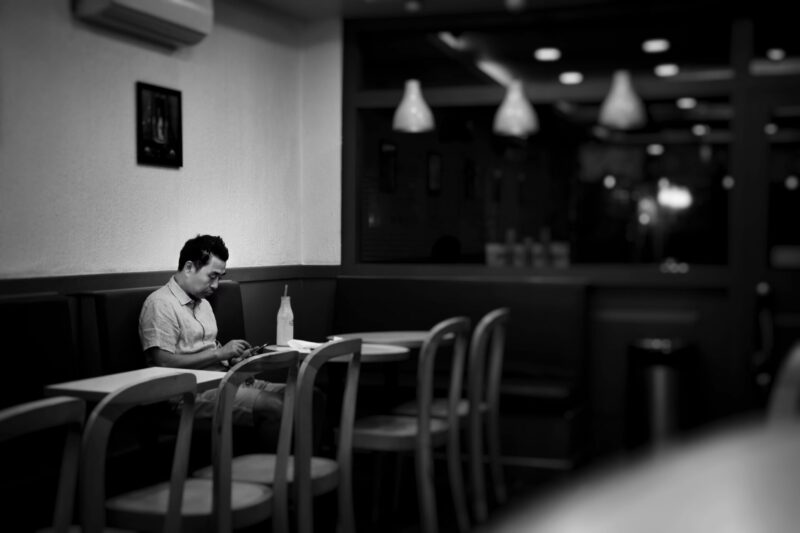 お店で一人で腰かけて本を読む男性